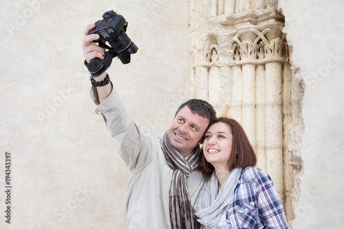 Traveling couple taking selfie together against ancient building background