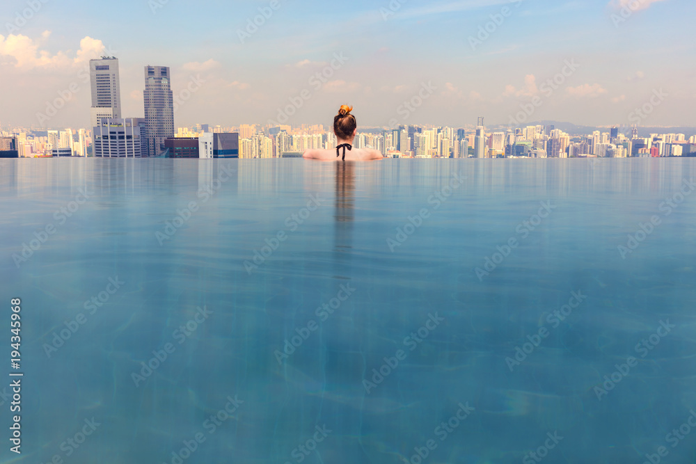 Fototapeta premium Kobieta, patrząc na pejzaż miejski, relaksując się w basenie bez krawędzi