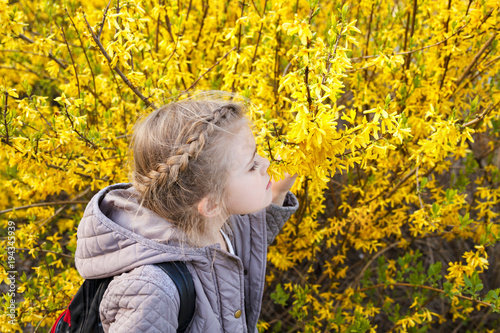 Pretty little girl in blossom yellow garden in beautiful sunny day