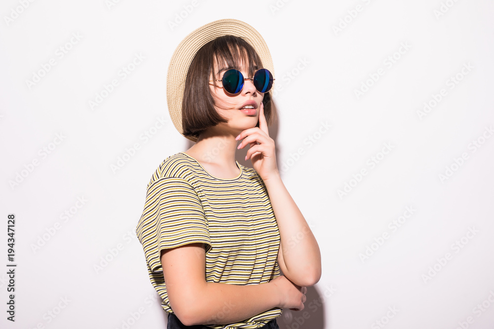 Young fashionable attractive hipster teen girl in sunglasses and straw hat isolated on white background .