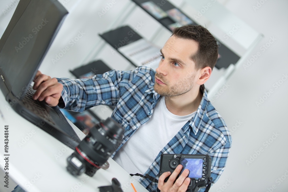 Man using laptop while repairing camera Man using laptop while repairing camera