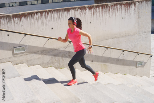 Young, fit and sporty woman running up the stairs. Fitness, sport, urban jogging and healthy lifestyle concept. © Acronym