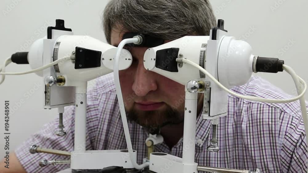 Patient in ophthalmology clinic. Man looks in synoptophore ophthalmic Instrument, used for