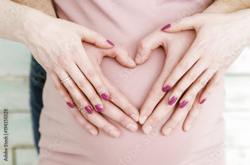 beautiful pregnant  woman with belly in pink dress  and heart