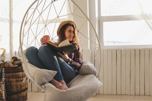 Girl relaxes reading a book and drinks tea.