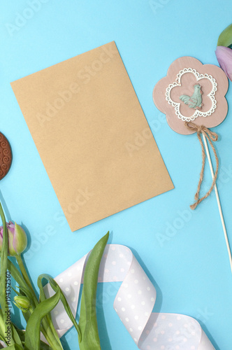 Spring tulip flowers, gift paper card on turquoise background from above in flat lay style. Greeting for Womens or Mothers Day.