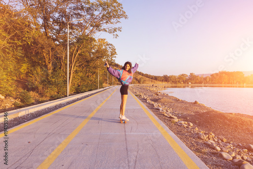 happy young woman on a skateboard on a summer day photo