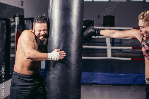 woman working out with boxing gloves and heavy punching bag with her couch