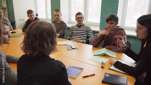 Teacher sits at a table and talks with students at university