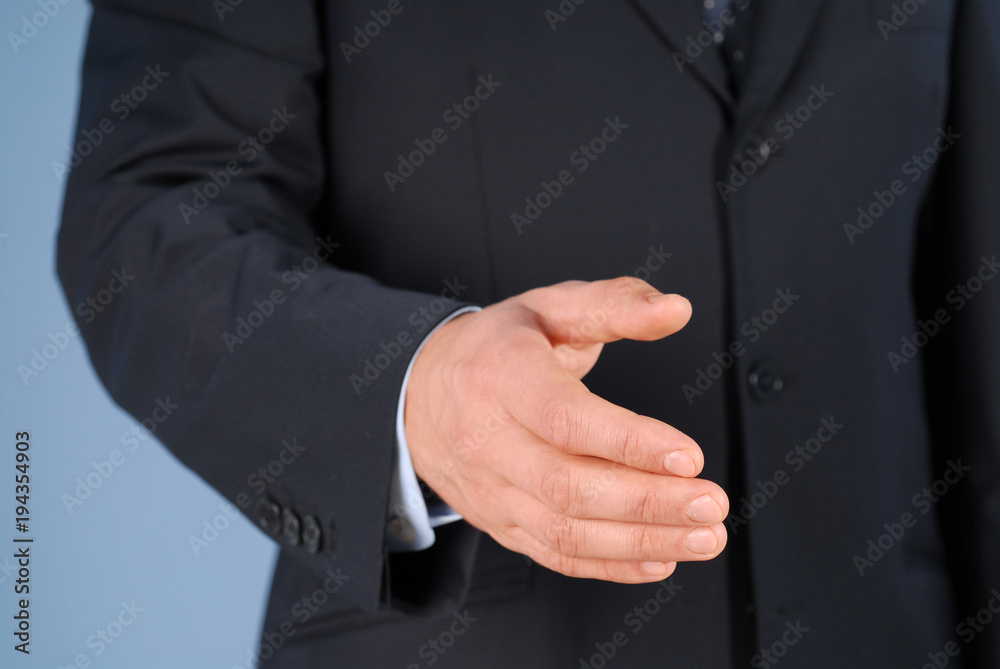 Fototapeta premium Closeup of a businessman in suit giving hand for handshake