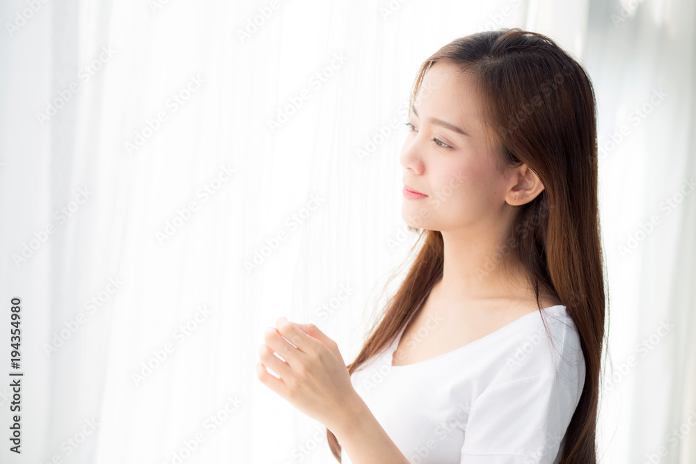 Beautiful young asian woman standing the window and smile while wake up with sunrise at morning, lifestyle and relax concept. Beautiful young asian woman standing the window and smile while wake up with sunrise at morning, lifestyle and relax concept.