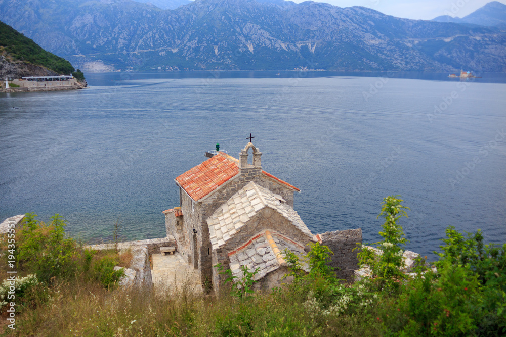 old stone Church in Boka Kotor Bay on background of the sea and the green mountains 