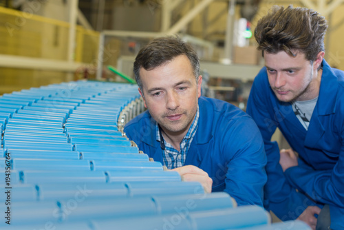 engineers looking at rolling conveyor belt in factory