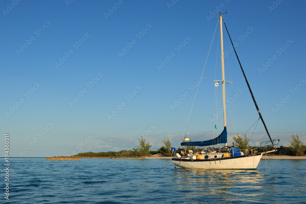 A gorgeous, traditional sailboat anchored out in the Bahamas.