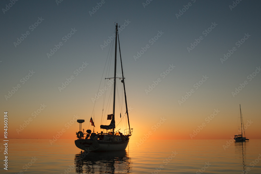 A couple of sailboats right at sunset in a calm anchorage in the Exumas Island chain in the Bahamas.