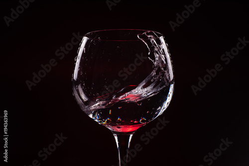 Red wine splashing out of a tall wine glass