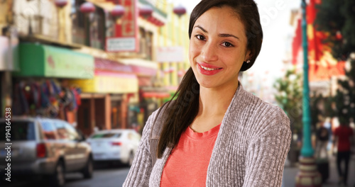 A Hispanic girl poses for a portrait in china town. A Latina woman looks at the camera and smiles in San Francisco
