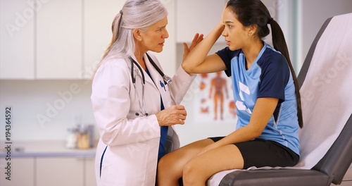 An injured soccer player goes to the doctors office for help. A footballer with a concussion seeks attention from a medical professional photo