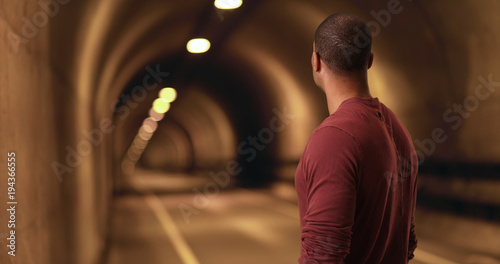 African American stares down a tunnel. A black man looks for a light at the end of the tunnel