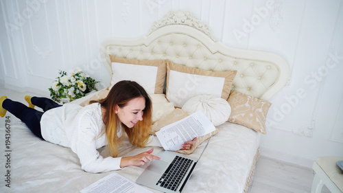 Smart Pretty Girl Reads and Rechecks Essay or Term Papers, Making Adjustments to Project Work Using Computer. Young Woman European Appearance With Long Blond Hair Looking at Camera and Smiling photo