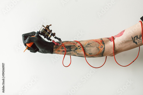 hand tattoo artist with the tattoo machine on a white background. the red wires