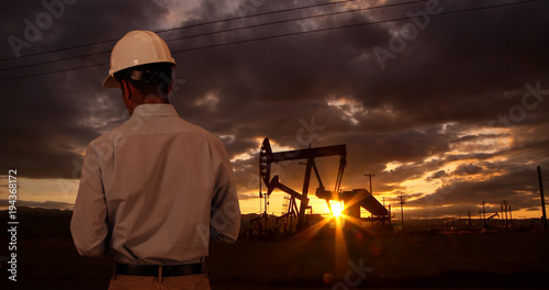 фотографія Engineer wearing hard hat helmet checking oil derrick field