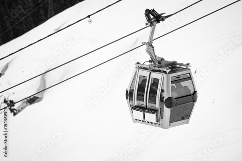 close up on cable cabin gondola taking people to the top of snowy mountain to ski slopes