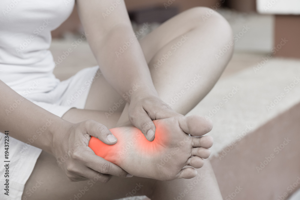Closeup young woman feeling pain in her foot at home. Healthcare and medical concept. Closeup young woman feeling pain in her foot at home. Healthcare and medical concept.