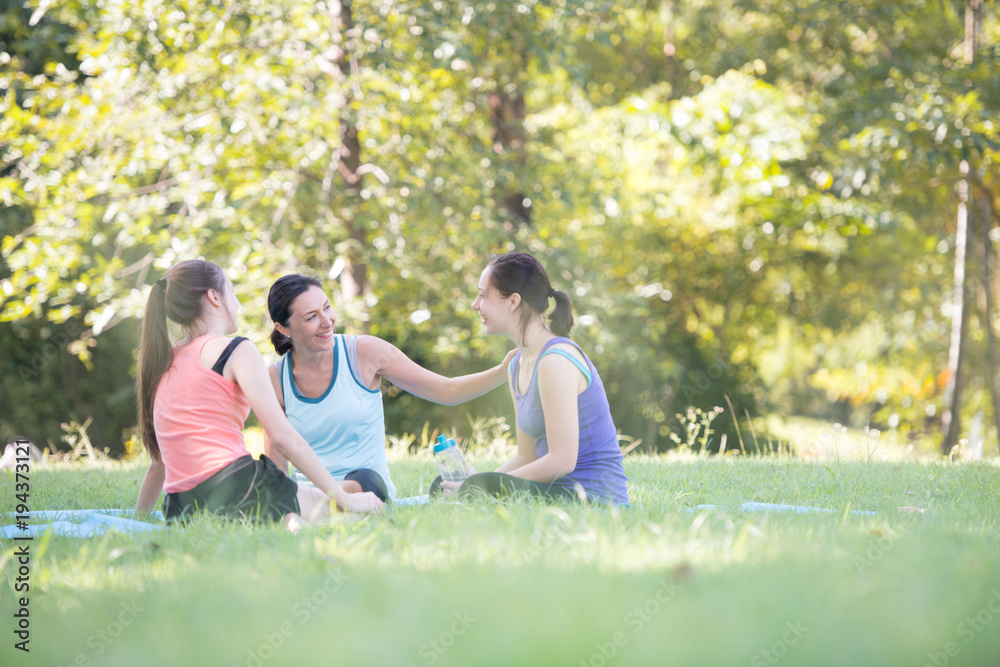 Families with young Russian mother and daughter are talk about exercise. After practice yoga at the park finished. Health and Fitness concept