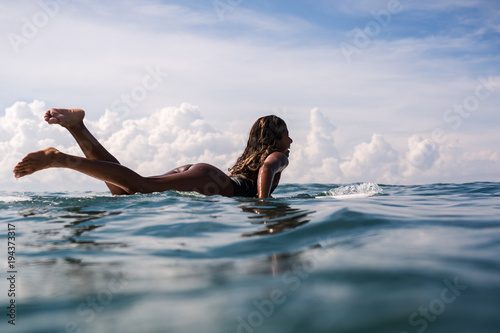 Photography Beautiful young indonesian woman in bikini surfing wave in Bali on the backgroun