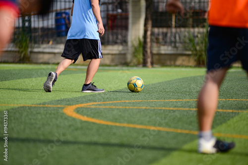 Unidentified group of male football players playing amateur football match on sunny summer day on simple sports venue