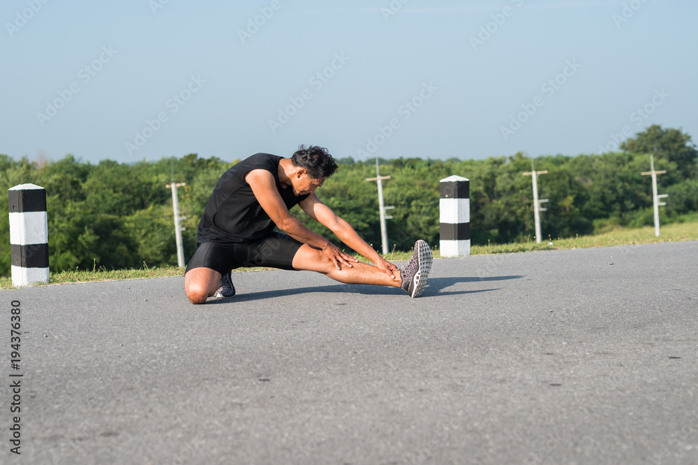 Male runners are stretching the leg muscles to prepare for a run in the morning. The concept of health and fitness