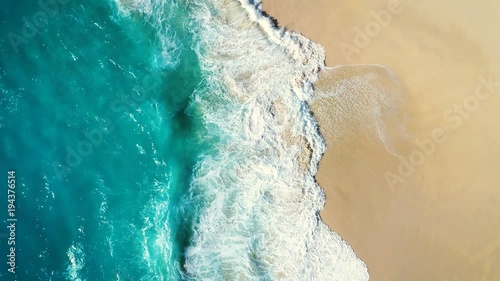 Aerial view waves break on white sand beach. Sea waves on the beautiful beach. drone 4k shot. zoom out