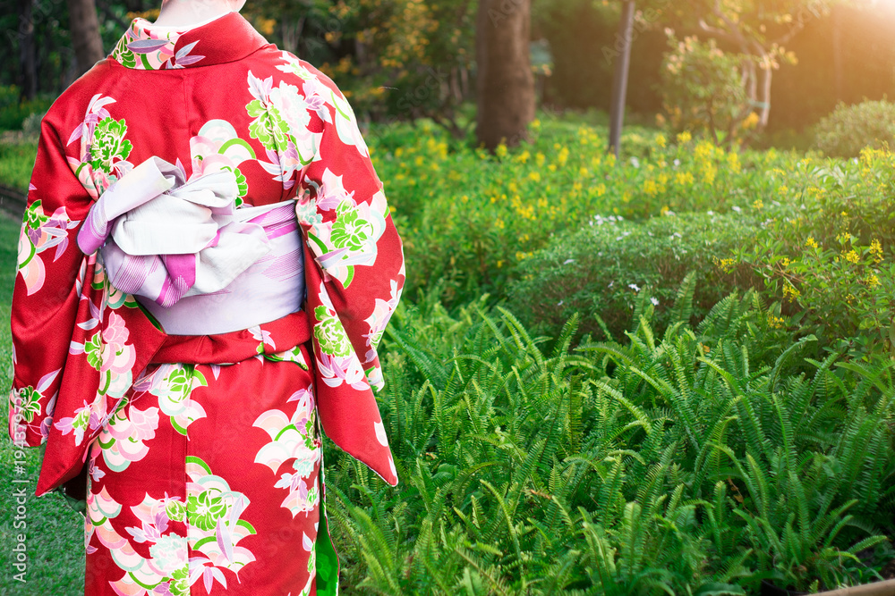 Young woman wearing Kimonos traditional fashion of Japan walking in the flowers garden. Young woman wearing Kimonos traditional fashion of Japan walking in the flowers garden.