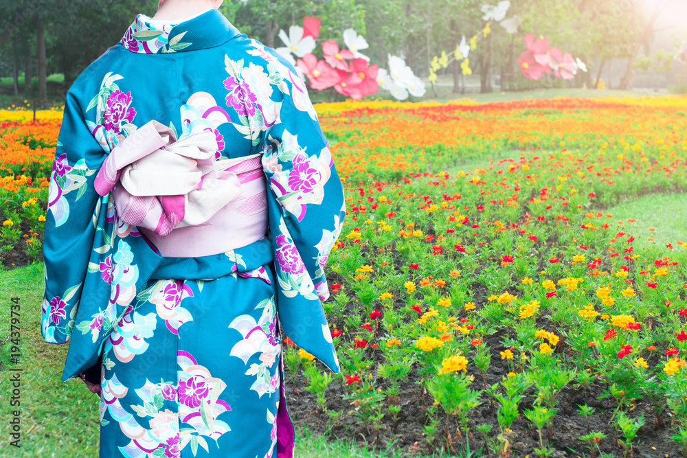 Young woman wearing Kimonos traditional fashion of Japan walking in the flowers garden. Young woman wearing Kimonos traditional fashion of Japan walking in the flowers garden.
