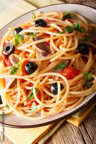 Italian pasta Alla Puttanesca with anchovies  tomatoes  garlic and black olives macro. vertical