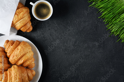 Croissants, coffee and sprouted wheat on a dark background. Breakfast flat lay.