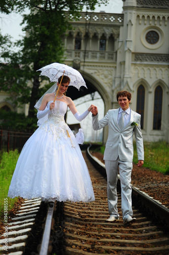 Newly-married couple walking on rails photo