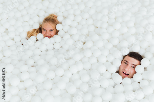 couple of loving friends have fun surrounded by white plastic balls in a dry swimming pool. photo