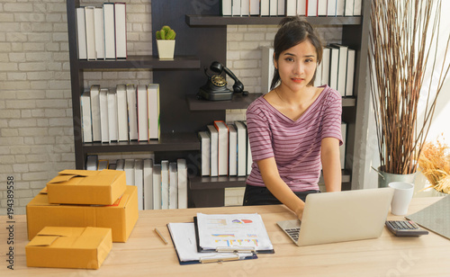фотографія Young Asian female business owner is using laptop in the home.