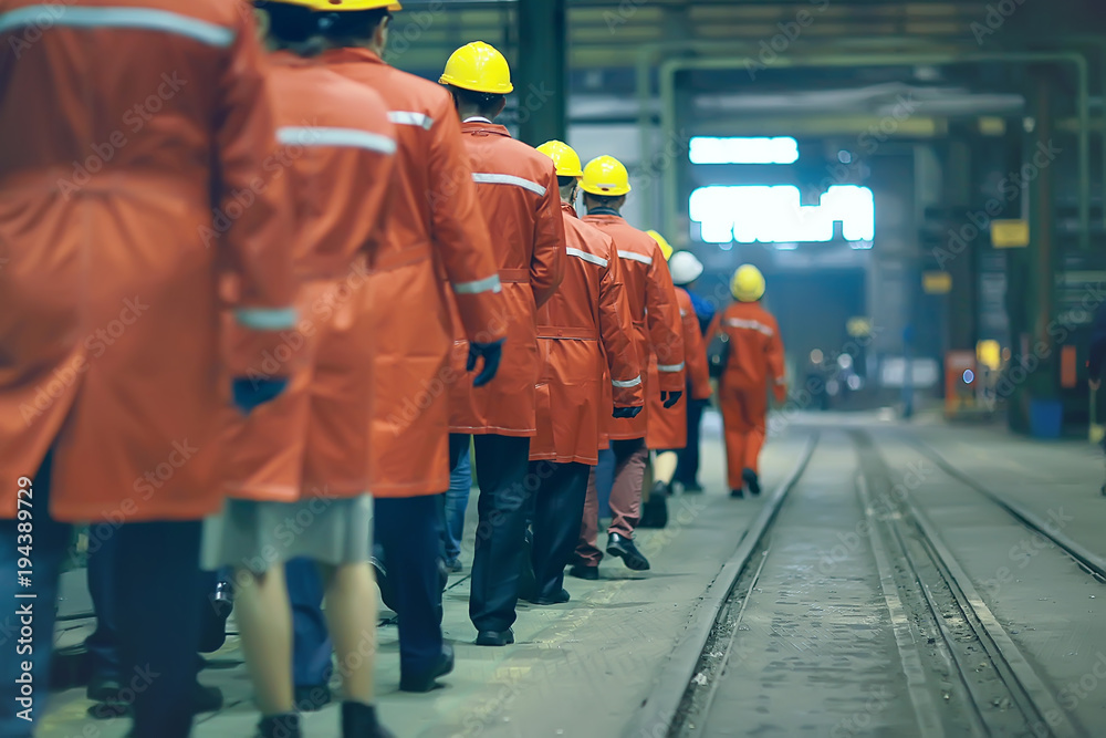 Obraz premium workers helmets at the factory, view from the back, group of workers, change of workers in the factory, people go in helmets and uniforms for an industrial enterprise