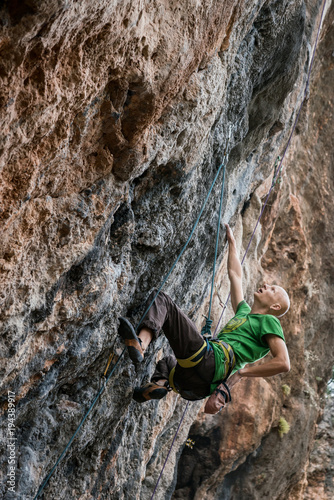 bald man climbs rock, side view, Turkey