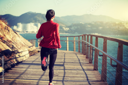 sporty fitness woman runner running on seaside boardwalk © lzf