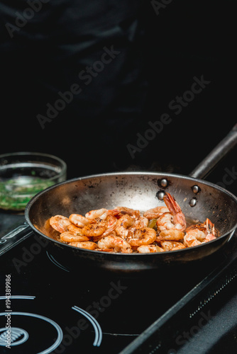 Shrimp on frying pan. Thermal processing of food. Electric cooker in a restaurant