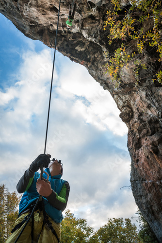 man belays climber on a rock, bottom view