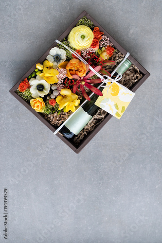 Bouquet of flowers with bottle of white wine in old wooden rustic box. Romantic present, beautiful floral arrangement