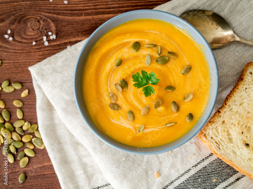 Dietary vegetarian pupmkin cream soup puree,  on dark brown wooden table, top view, close up. photo