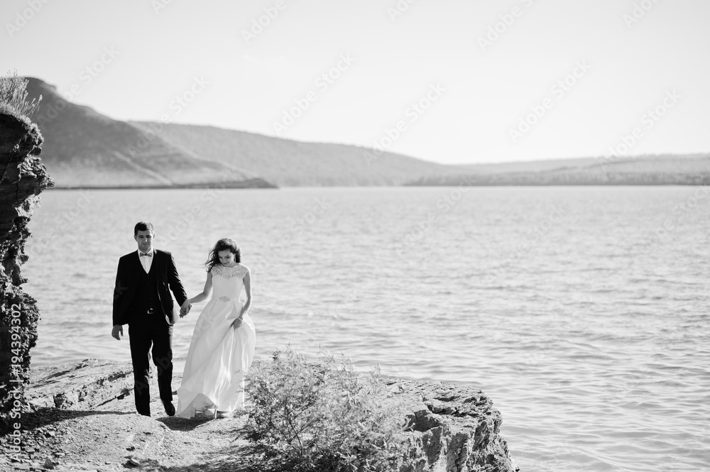 Wedding couple at breathtaking landscape with rock and lake.