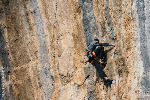 Man climbs a yellow rock with a rope, lead