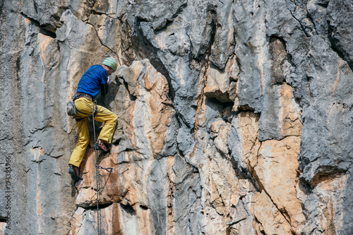 Man climbs a yellow rock with a rope, lead